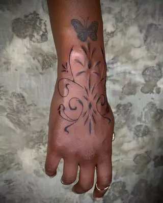 Swirly hand tattoo with butterfly on wrist