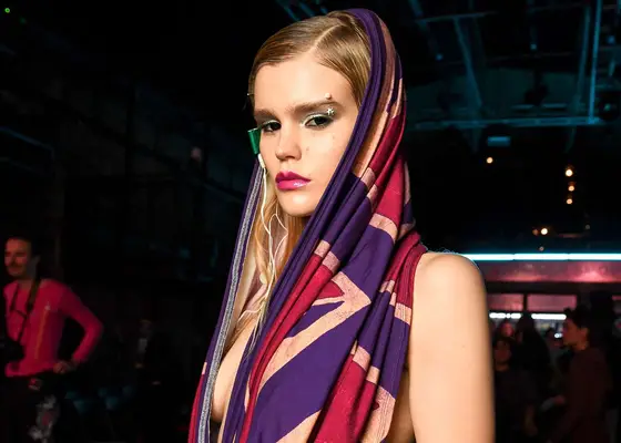 blonde model backstage at sinead gorey show in london with eyebrow piercing and cape