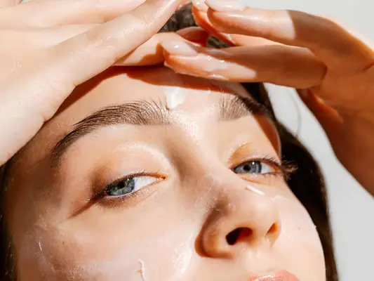 Woman applies skincare to her forehead