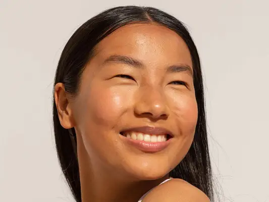 Person looking over their shoulder smiling with clear skin