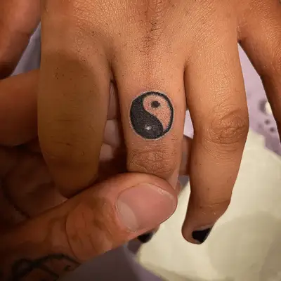 Close up of a finger with a yin-yang symbol tattoo.