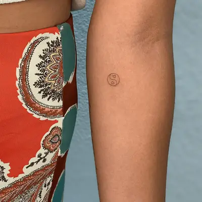 Close up of a yin and yang tattoo with mini heart details.