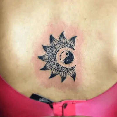 Close up of a back tattoos with a sun eclipsing a yin and yang symbol.
