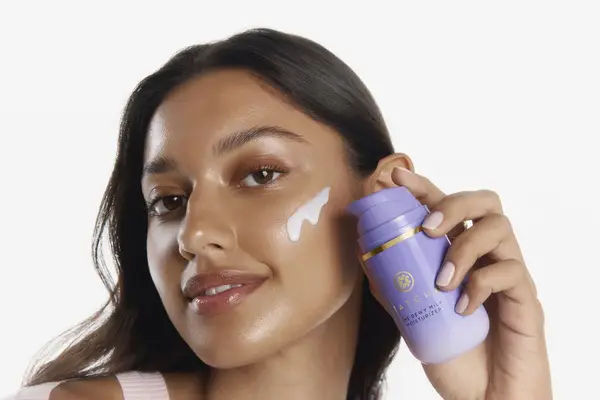 model applying Tatcha Dewy Milk Moisturizer
