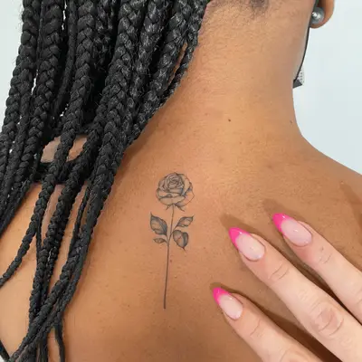 single flower with stem back tattoo 