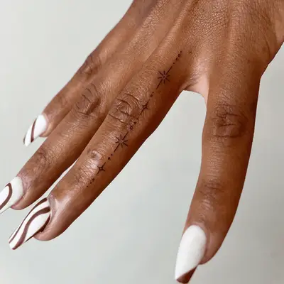 fine finger tattoo of small stars in a line