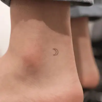 tiny crescent moon tattoo on outer ankle 