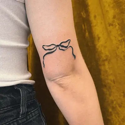 tattoo of ribbon tied in a bow above elbow