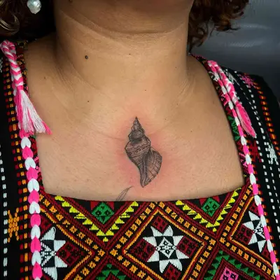 black ink seashell tattoo in middle of chest below neck