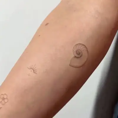 black ink sprial shell tattoo on forearm