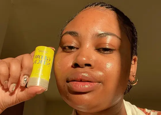 woman with glowy skin holding sunscreen stick