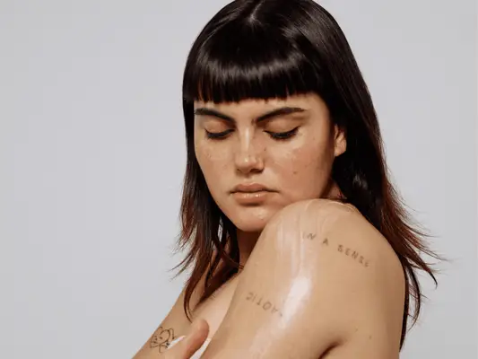 Close up of a woman looking down at her arm tattoos.