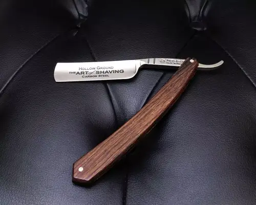 The Art of Shaving straight razor with wooden handle on leather cushion