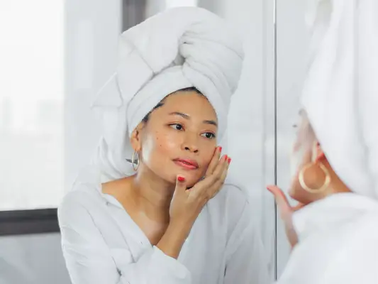 woman wearing hair towel and looking in mirror