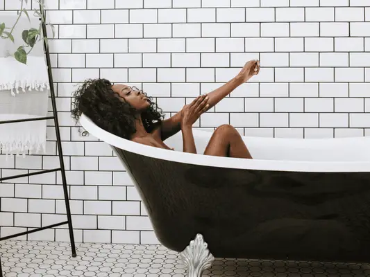 A woman in a claw foot bath tub in a clean, calm bathroom setting