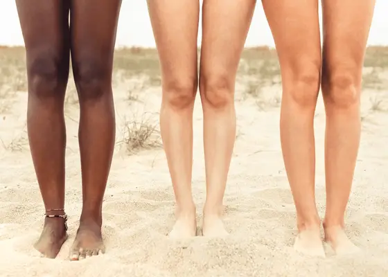 Three pairs of bare legs on the beach