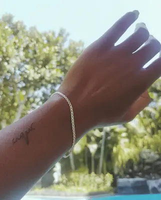 Close up of a hand with a script tattoo on the forearm