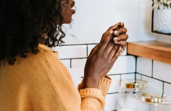 woman washing hands in tiled bathroom