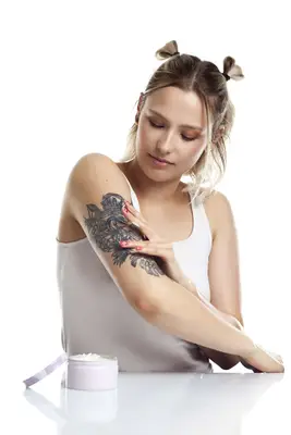 woman putting lotion on tattoos