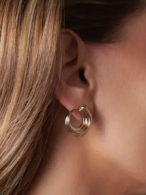 Close-up of woman wearing gold circular stud earring in earlobe