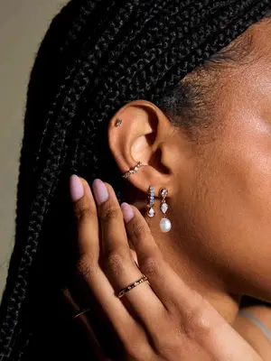 Close-up of woman with braided hairstyle wearing earrings with gems including conch piercing