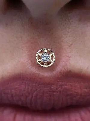 Close-up of person with philtrum piercing with star-shaped jewelry with gem