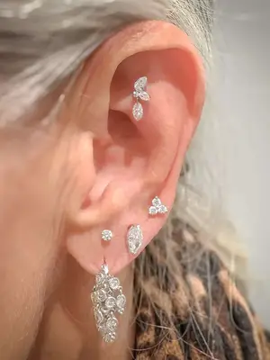 Close-up of woman with silver hair and multiple sparkly ear piercings including faux rook