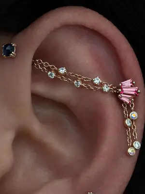 Close-up of ear with chaindustrial piercing with multiple gemstones