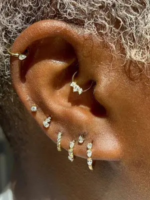 Close-up of woman with multiple sparkly ear piercings including daith hoop at center