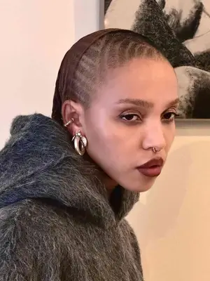 Close-up of an ear with multiple earrings and a hand touching the side of the face