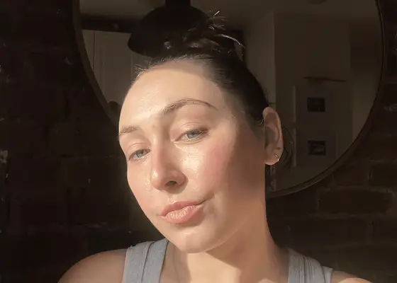 Woman with hair pulled back into a bun and rosy, glowy skin