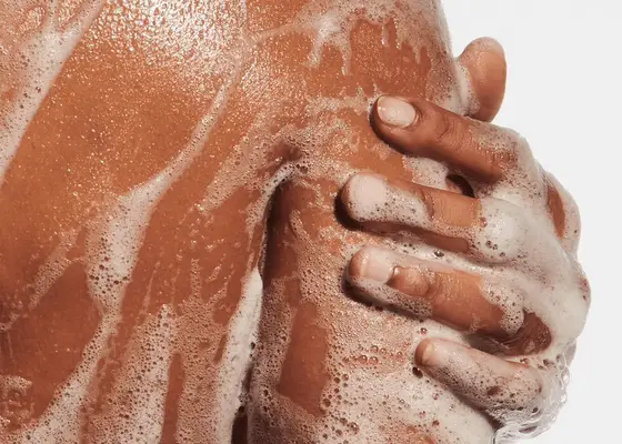 Hand touching the back of an arm/shoulder covered in soap