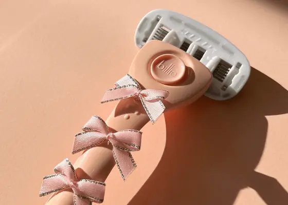 close up of pink razor with bows on pink background