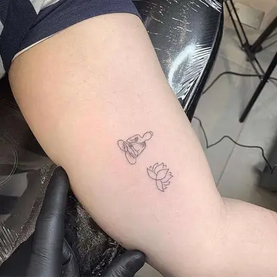 Image of an inner arm tattoo with a lotus and buddha design