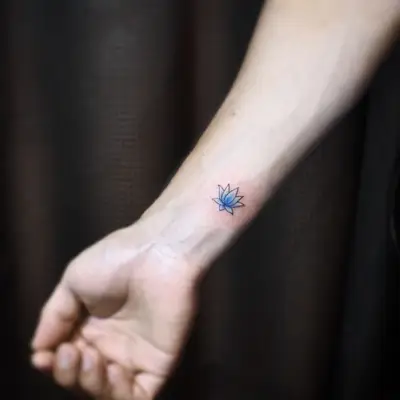 Image of a cartoonish blue lotus flower tattoo above the wrist