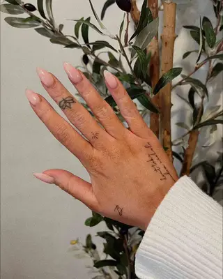 Image of a hand with a lotus tattoo on the middle finger and other hand tattoos
