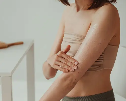 Woman applying lotion on her arm, moving toward her elbow.
