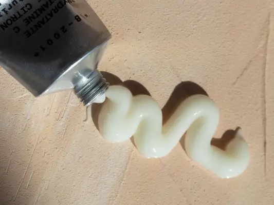 Close up of a tube of lotion squeezed on a textured pink-ish background