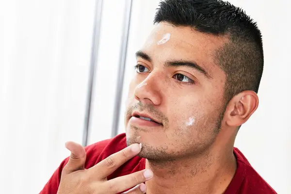 A person dabs moisturizing cream on their face