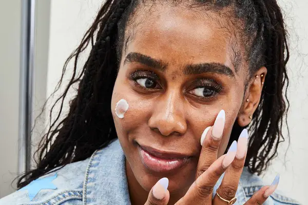 Woman applies Shani Darden Hydration Peptide Cream to her cheek