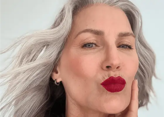 Woman with long gray hair wearing bright red lipstick