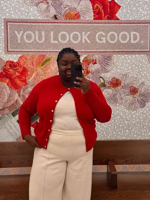 Abisola Omole wears a red cardigan, white sweater and pants