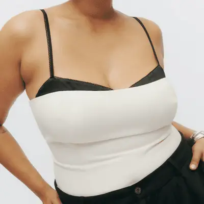 Photo of woman wearing cream tube top with exposed black bra underneath 