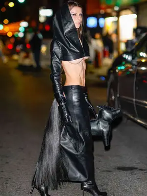 Julia Fox wearing a black leather hooded crop top with black leather pants and a black tail 