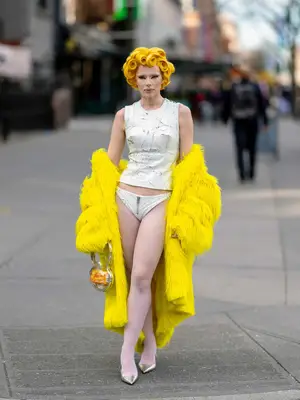Julia Fox wearing a white top with coordinating underwear and a yellow fur coat and yellow hair
