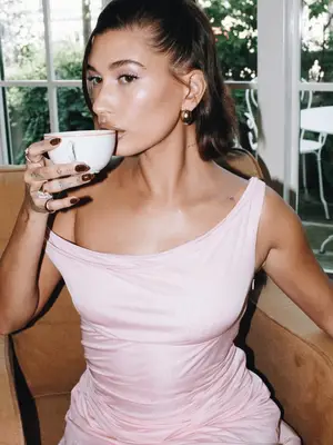 hailey bieber wears millennial pink dress and sips from teacup