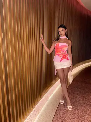 Madison Bailey wears a pink mini dress with floral design, sequined skirt, and matching scarf