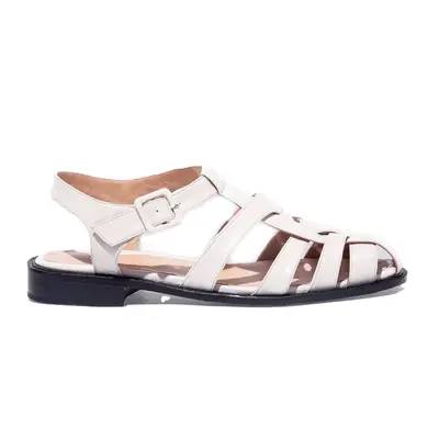 Woman wearing an orange top, white pants, and dark green boots