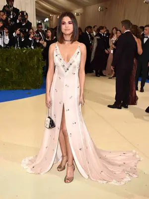 Selena Gomez wears a lace-embroidered coach gown and matching purse to the 2017 Met Gala