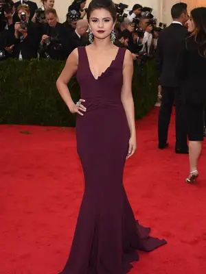 Selena Gomez wears a sleeveless burgundy Diane von Furstenberg gown to the 2014 Met Gala